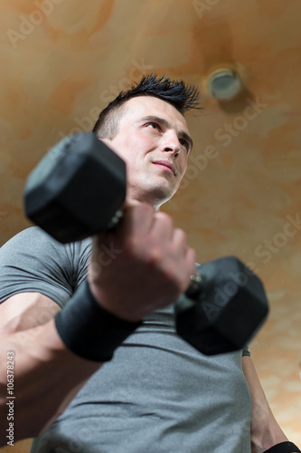 Young Man Working Out Biceps - Dumbbell Concentration Curls © Myvisuals