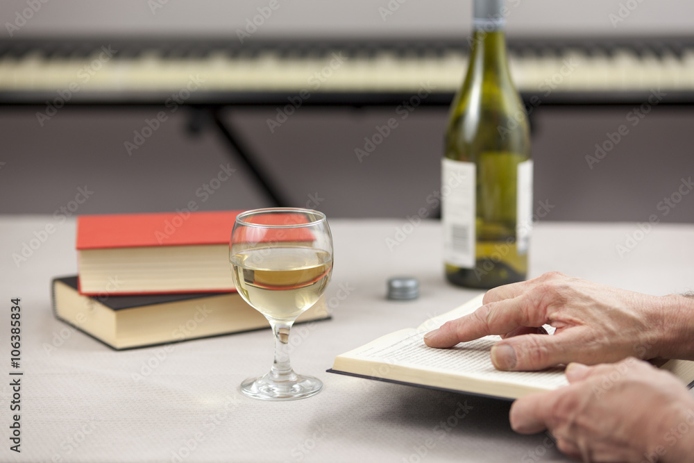 Person reading at table with a glass of wine