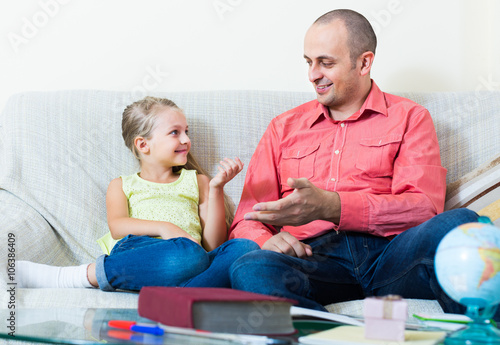 Portrait of father and little girl discussing something  indoors