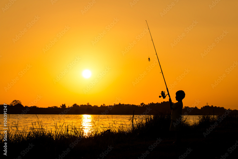 little boy fishing in the river sunset background