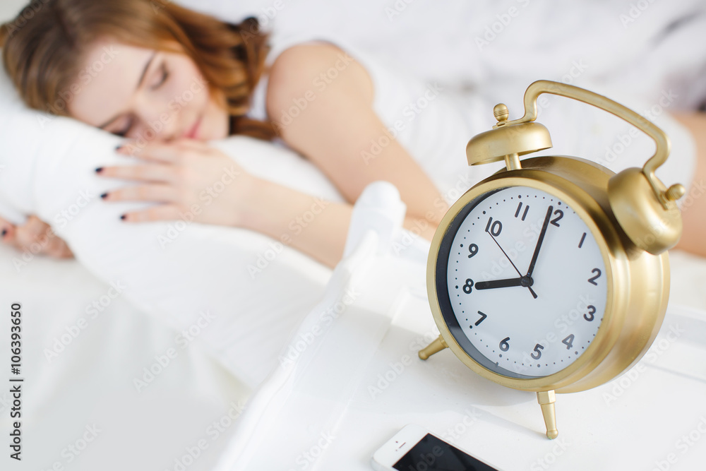 Sleeping girl with alarm clock on a white background Sleeping girl with alarm clock on a white background