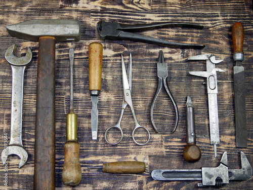 A collection of vintage tools displayed on a background of brown barnboard.