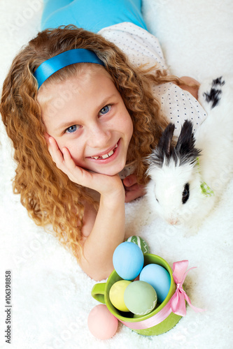 Cute little girl with a bunny rabbit has a easter at white carpe