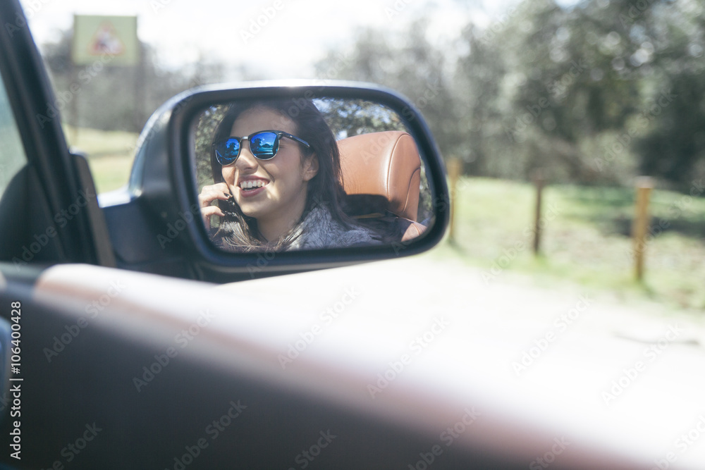 Woman sitting on the passenger seat of a convertible car smiling