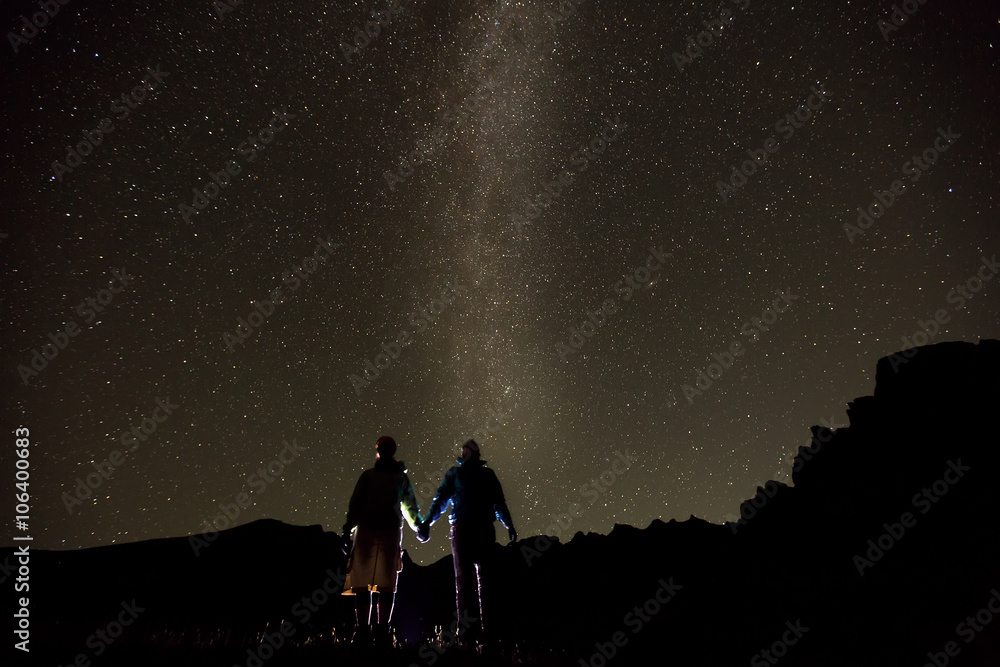 Couple is standing in mountains against night sky with milky way Couple is standing in mountains against night sky with milky way