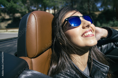 Woman with sunglasses sitting in a convertible car