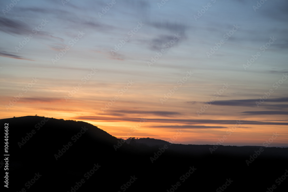 Beautiful Vibrant sunset landscape over countryside hills silhou
