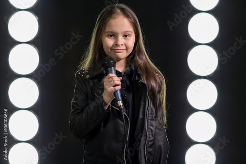 Little girl singing in front of stage lights