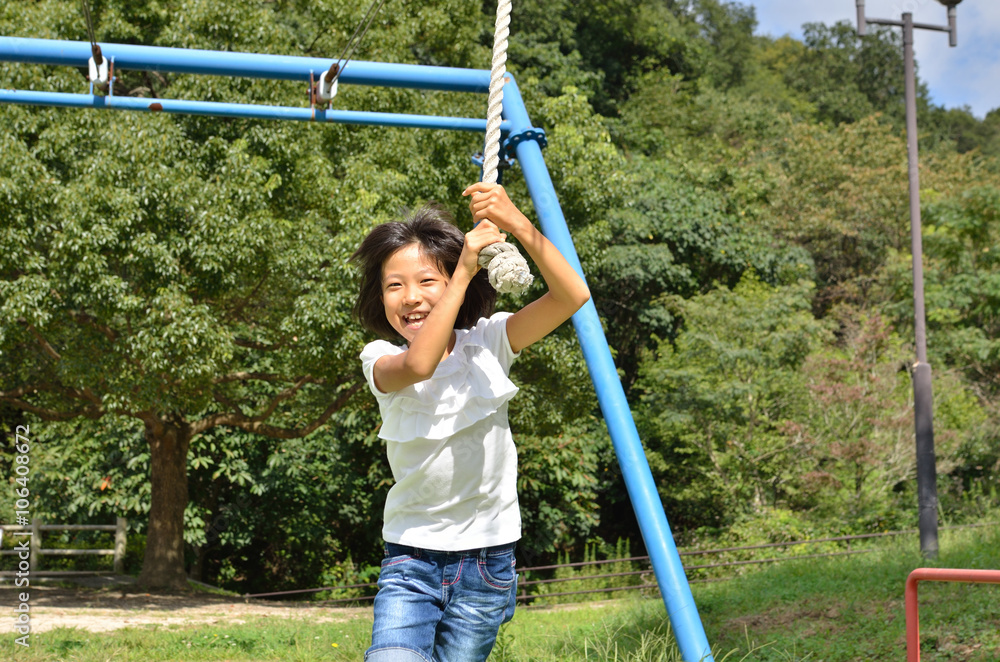 Fototapeta premium 公園の遊具で楽しく遊ぶ女の子