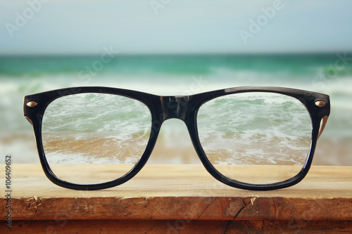 hipster glasses on a wooden rustic table in front of the sea background. vintage filtered 