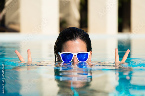 Summer fun and vacation concept. Playful woman doing success and victory gesture in swimming pool.