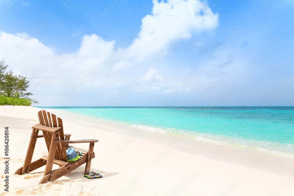 Wooden beach chair with hat and slippers at tropical beach, summer holiday concept