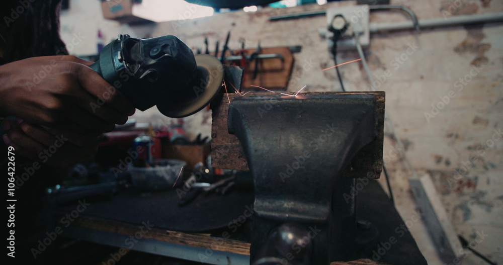 Craftsperson skillfully working a grinder in a grungy workshop Craftsperson skillfully working a grinder in a grungy workshop
