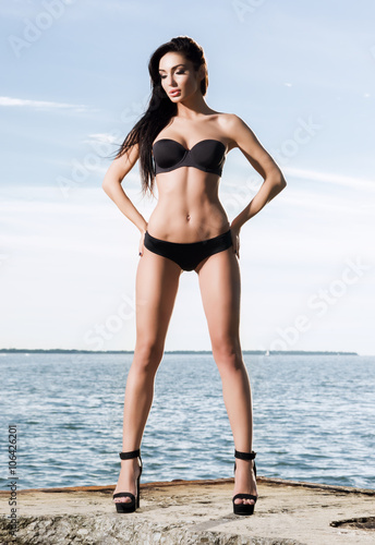 Beautiful and fit fashion model in a swimsuit on a pier