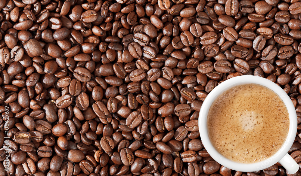 Obraz premium Close-up of coffee beans background and white coffee cup
