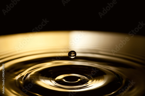 Dropping water bubble. Rings waves in dark bronze and black splashing background. macro view, soft focus, shallow depth of field. copy space