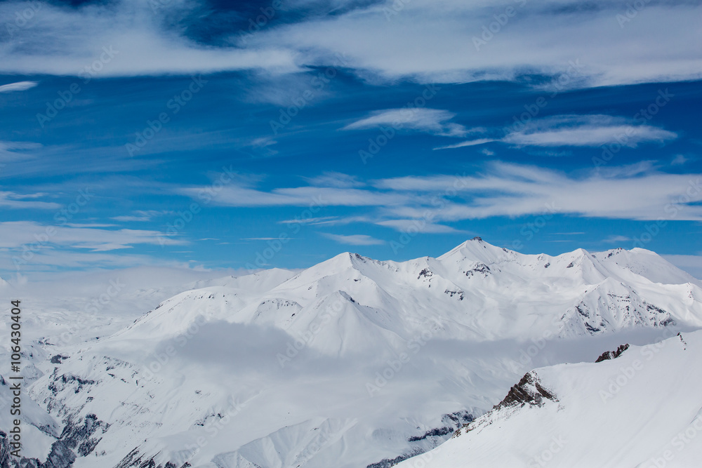 Beautiful blue skies with clouds over the mountains in the snow. Winter landscape