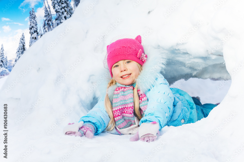 Little girl crawl through snow tunnel in park