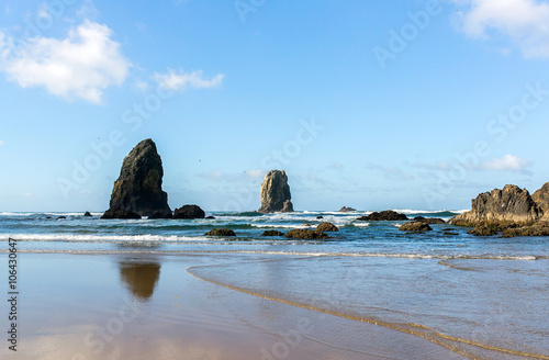 deserted west coast landscape with the needles of cannon beach in the united states of america during a sunny day on the pacific coast scenic byway with the ocean, waves, rock,