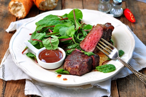 Medium steak with salad and barbecue sauce