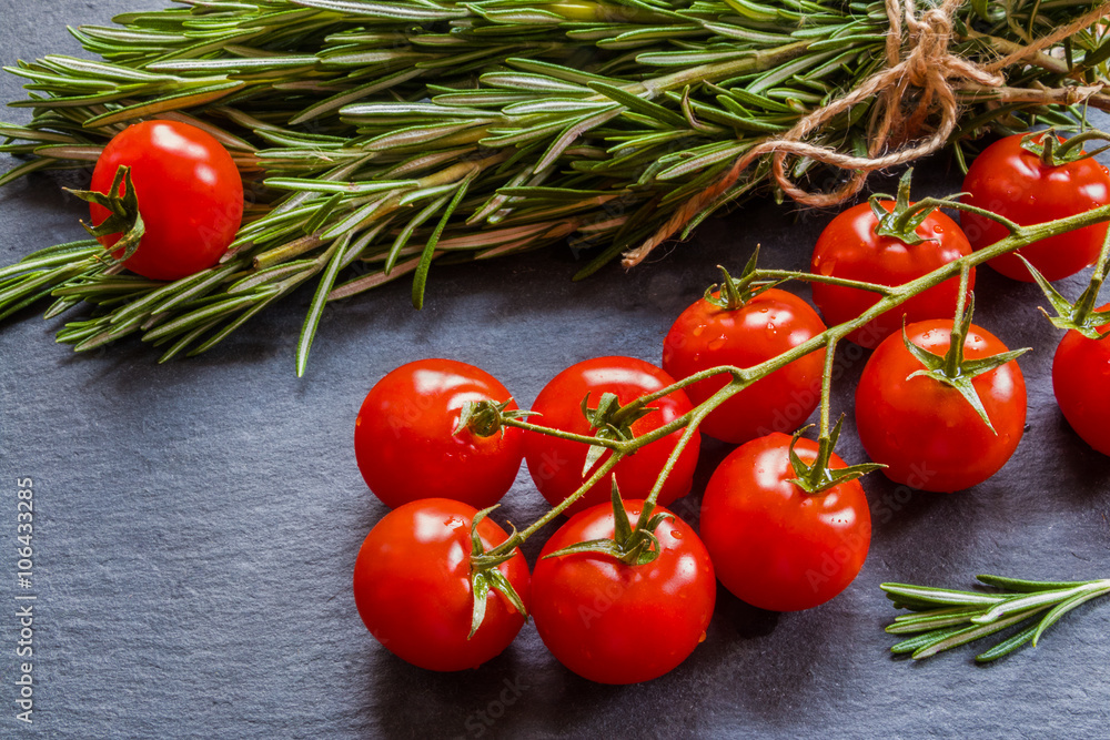 Fresh rosemary and tomatoes on the black background. Fresh rosemary and tomatoes on the black background.