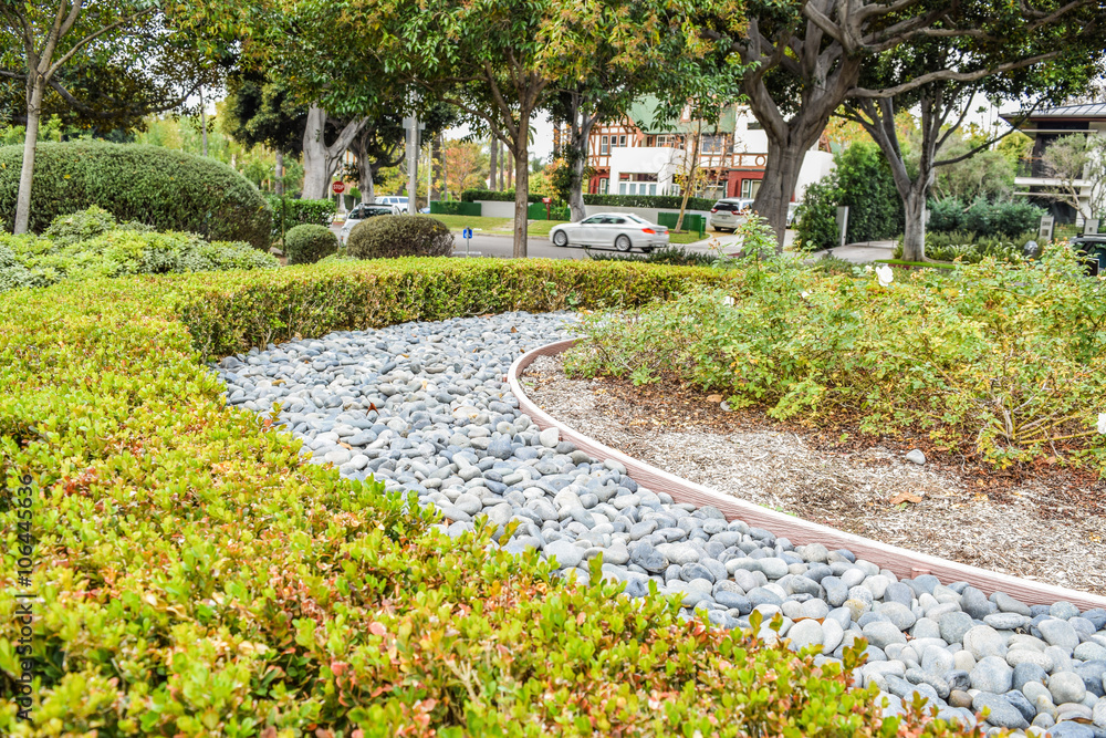 Fototapeta premium Beverly Gardens Park Nicely trimmed bushes, flowers and stones in front of the house, front yard. Landscape design.