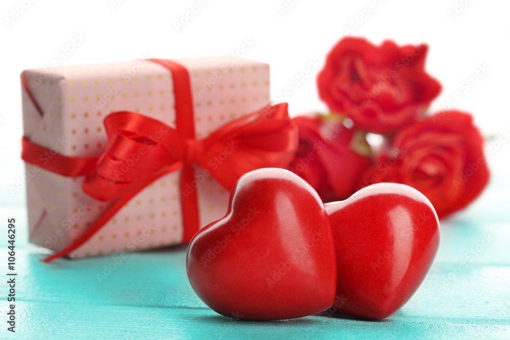 Gift box, rose flowers and decorative hearts on color wooden table, on light background Gift box, rose flowers and decorative hearts on color wooden table, on light background