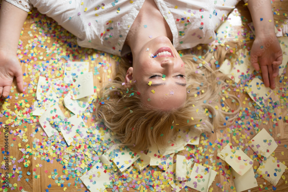 Cheerful young woman is stretching out her hands while confetti