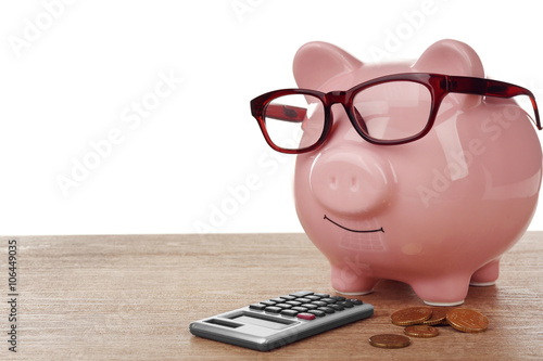 Pink piggy bank with glasses and calculator on white background
