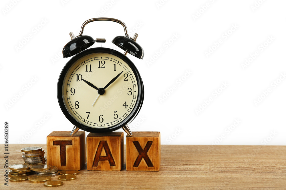 Tax time and alarm clock with coins on table Tax time and alarm clock with coins on table