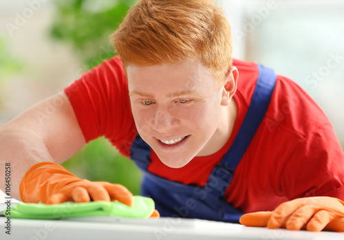 Young janitor cleaning tabl...