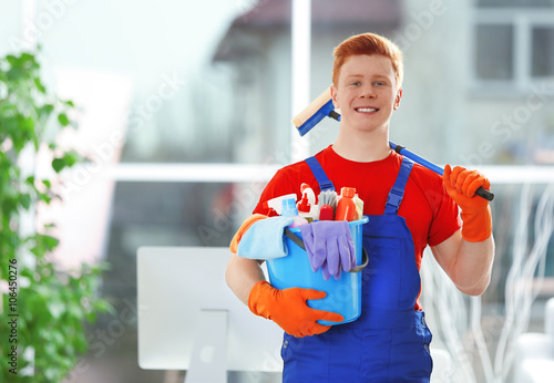 Young janitor holding clean...