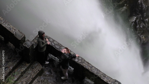 Adult women tourists waving at the camera on Pailon del Diablo waterfall,a popular tourist destination in Ecuador,offering breathtaking natural beauty and adventure.