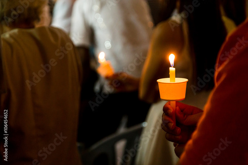 Closeup of people holding candle vigil in darkness  seeking hope