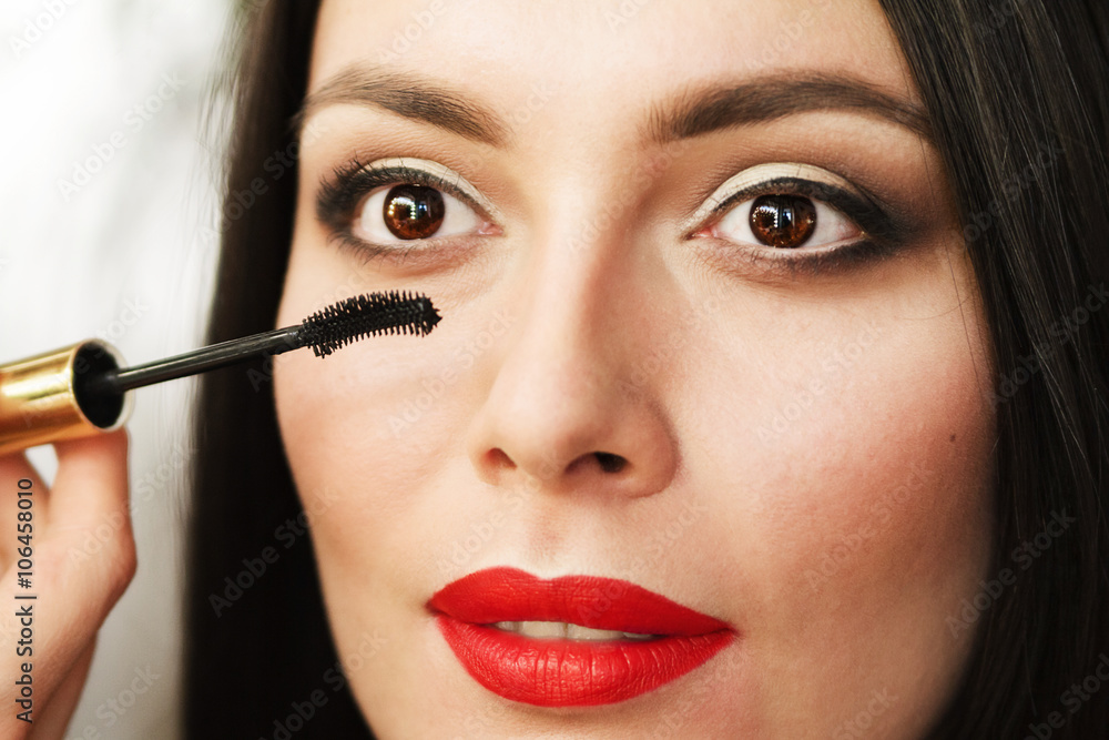 beautiful young brunette woman doing makeup.
make up eyelashes