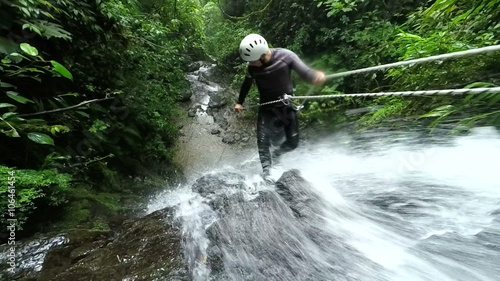 Experience the thrill of canyoning as our expert instructor showcases their rappelling skills near a breathtaking waterfall in mesmerizing slow motion footage.
