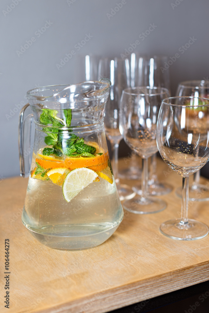 A carafe of fruity beverage with mint and lemon and wooden tray of appetizers at a banquet on a decorated tea table. Beautifully decorated table set in the restaurant. A carafe of fruity beverage with mint and lemon and wooden tray of appetizers at a banquet on a decorated tea table. Beautifully decorated table set in the restaurant.