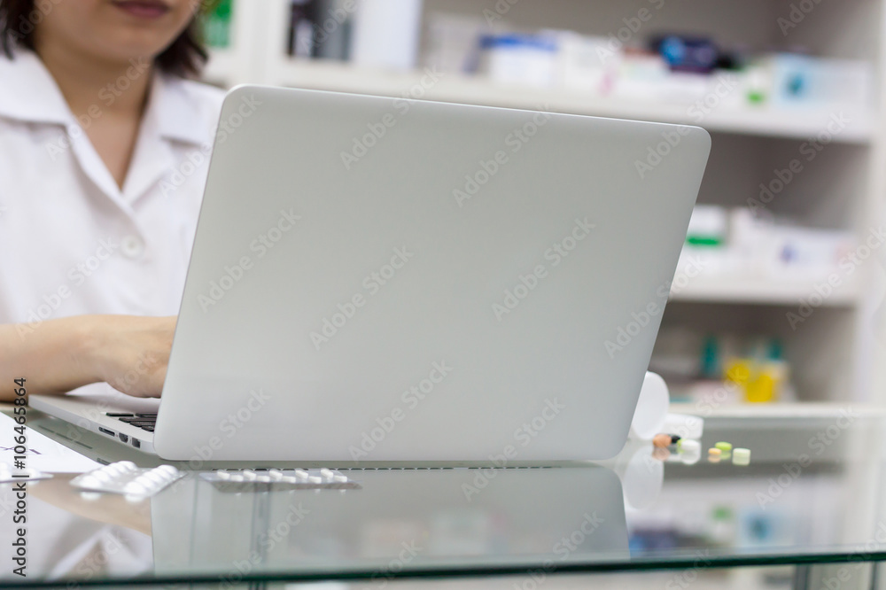 Pharmacist with laptop computer and medication in the pharmacy Pharmacist with laptop computer and medication in the pharmacy