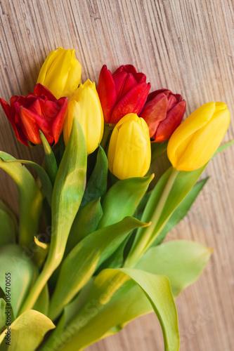Red and yellow tulips on a wooden table