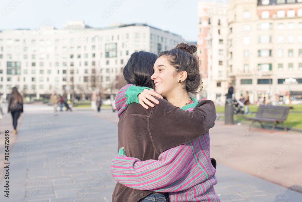 Two woman friends hugging in the street.