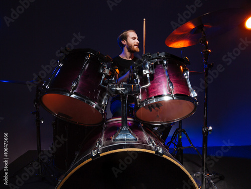 Attractive bearded man drummer sitting and playing on his kit