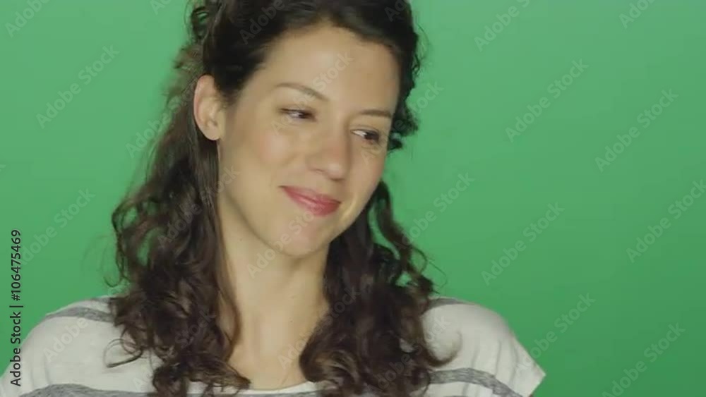 Young woman smiling and looking shy, on a green screen studio background Young woman smiling and looking shy, on a green screen studio background
