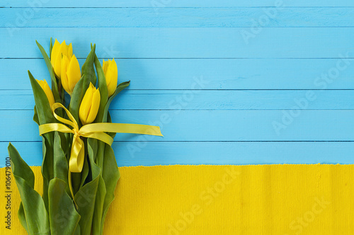 Background with bouquet of yellow tulips on blue painted wooden