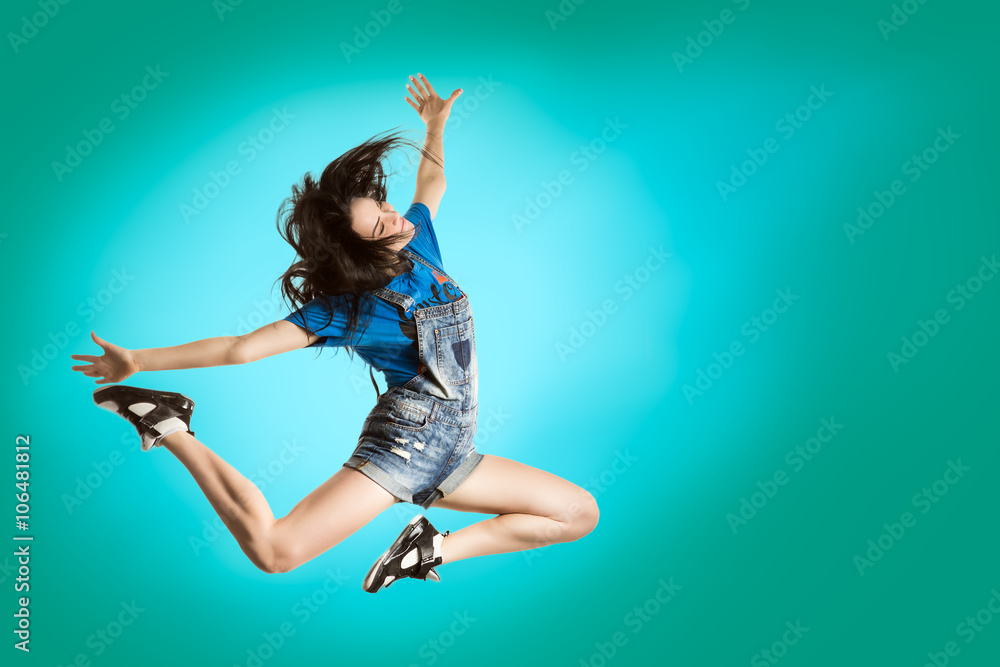 Modern style happy girl dancing on fresh blue background. Hip Hop dancer jumping concept.