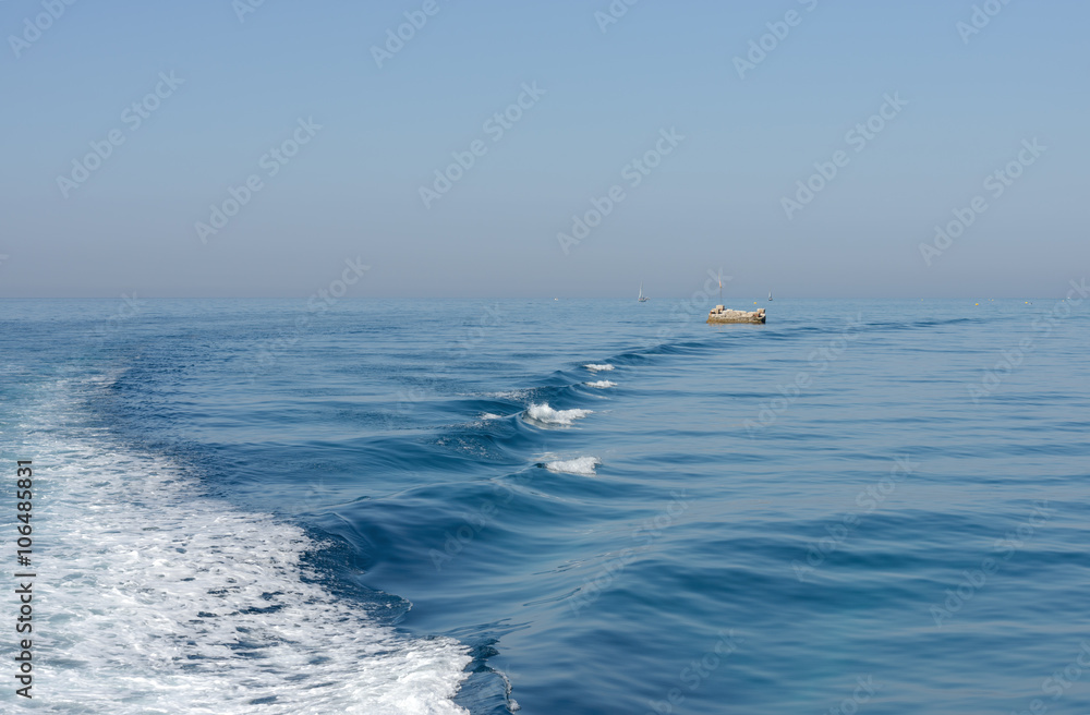 Seascape of with wave and foamy trail astern.