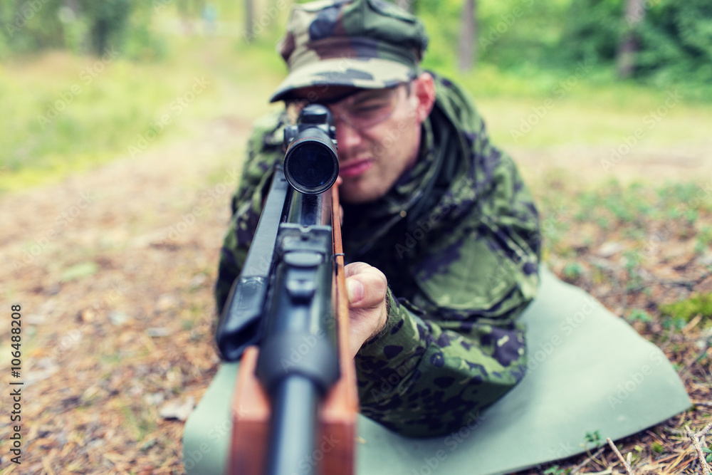 close up of soldier or hunter with gun in forest