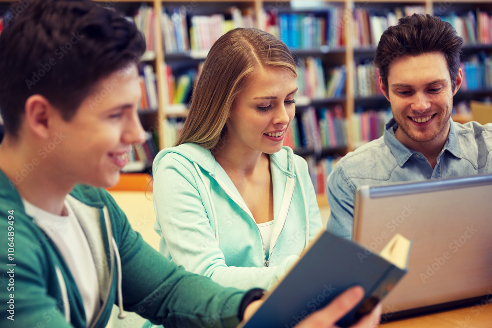happy students with laptop and book at library happy students with laptop and book at library