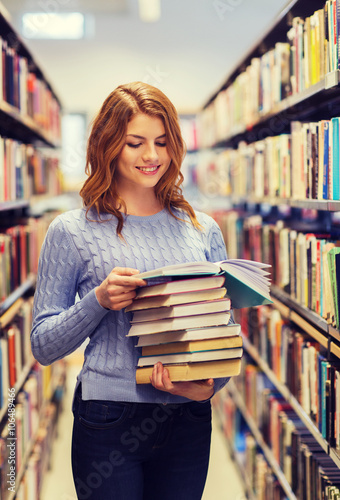 happy student girl or woman with books in library