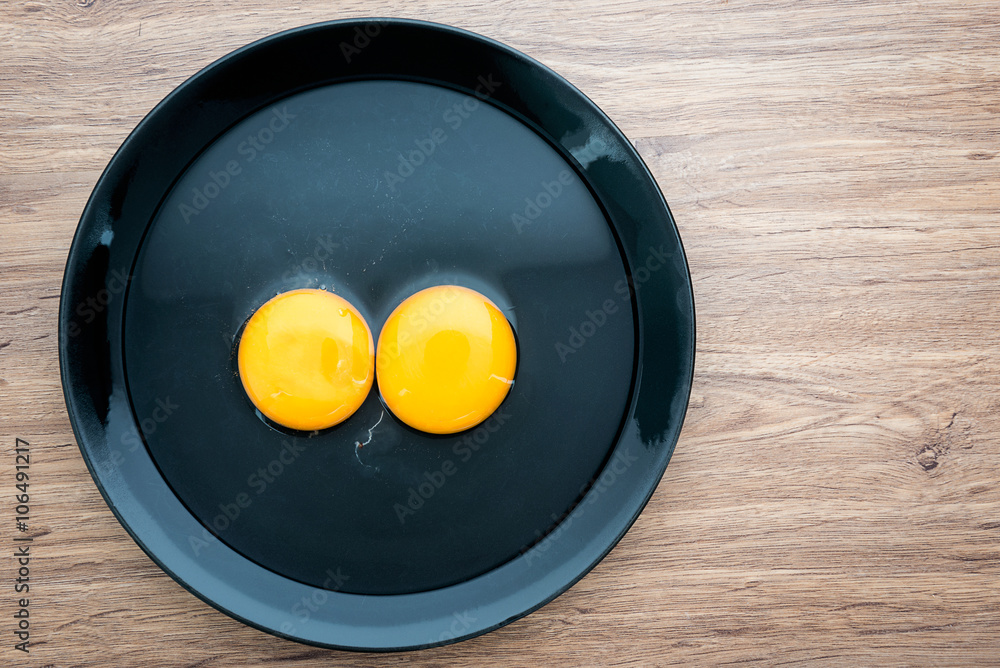 Top view of fresh eggs in black dish on wood background Top view of fresh eggs in black dish on wood background