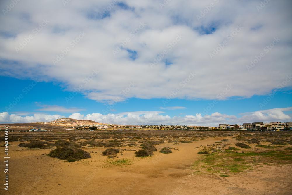 The barren landscape of Fuerteventura on a warm, sunny day, with a decent amount of cloud cover.